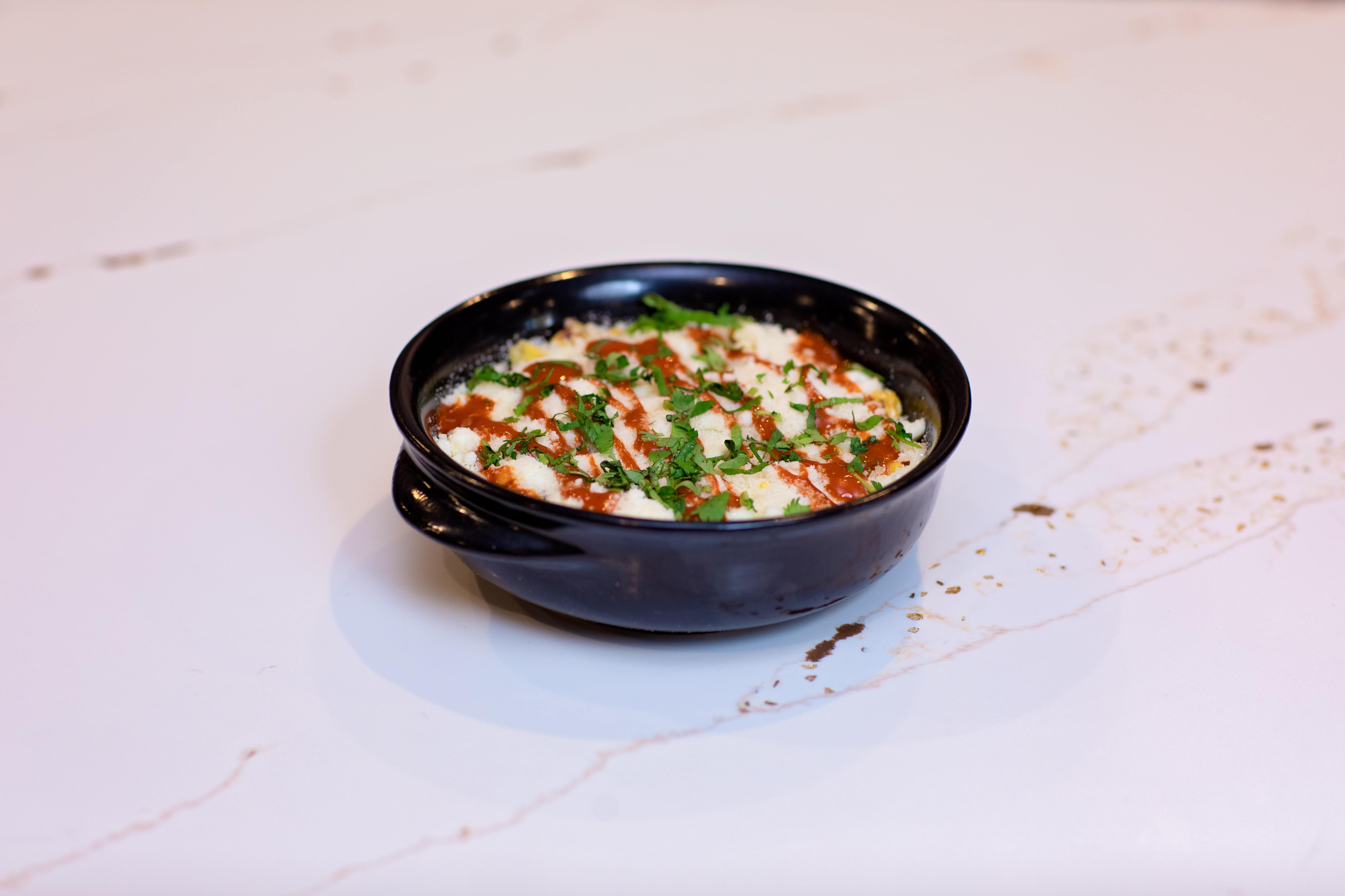 Elote-style corn in a dark ceramic bowl