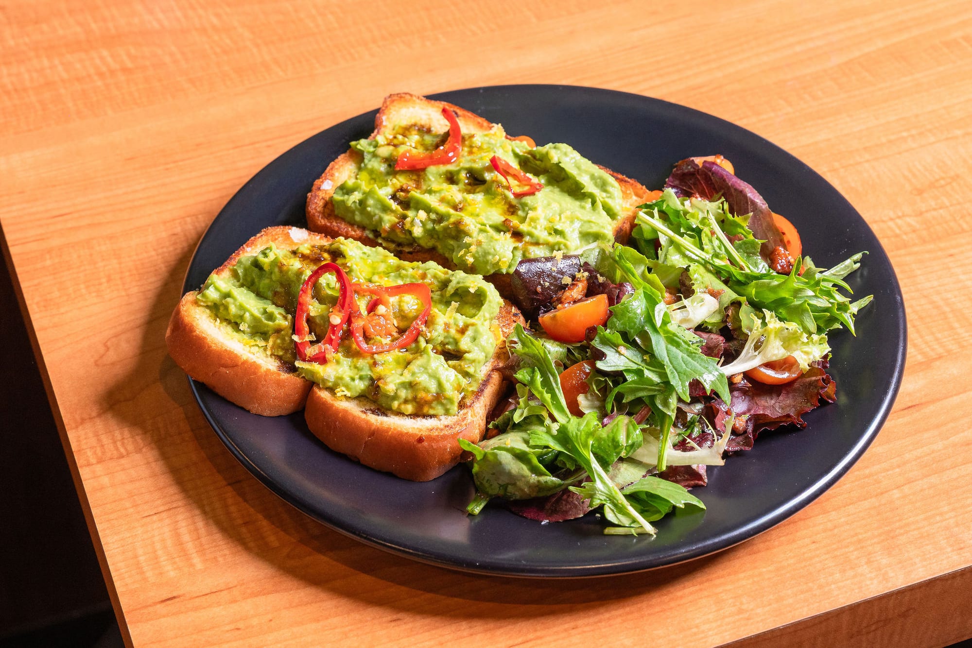 Avocado toast with chili and tomato, served with a side salad
