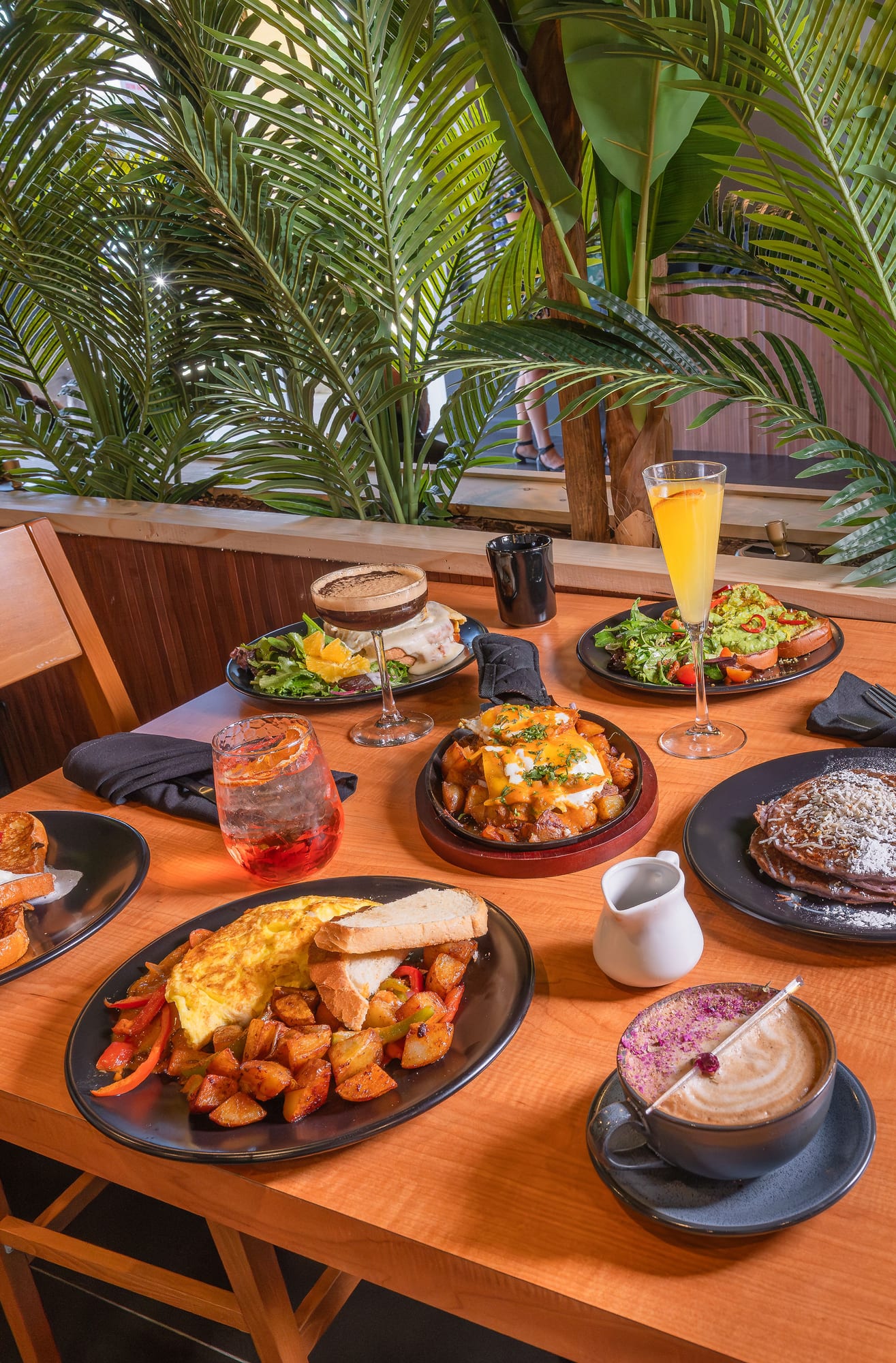 A brunch spread across the table — skillets, eggs, toast, and mimosas