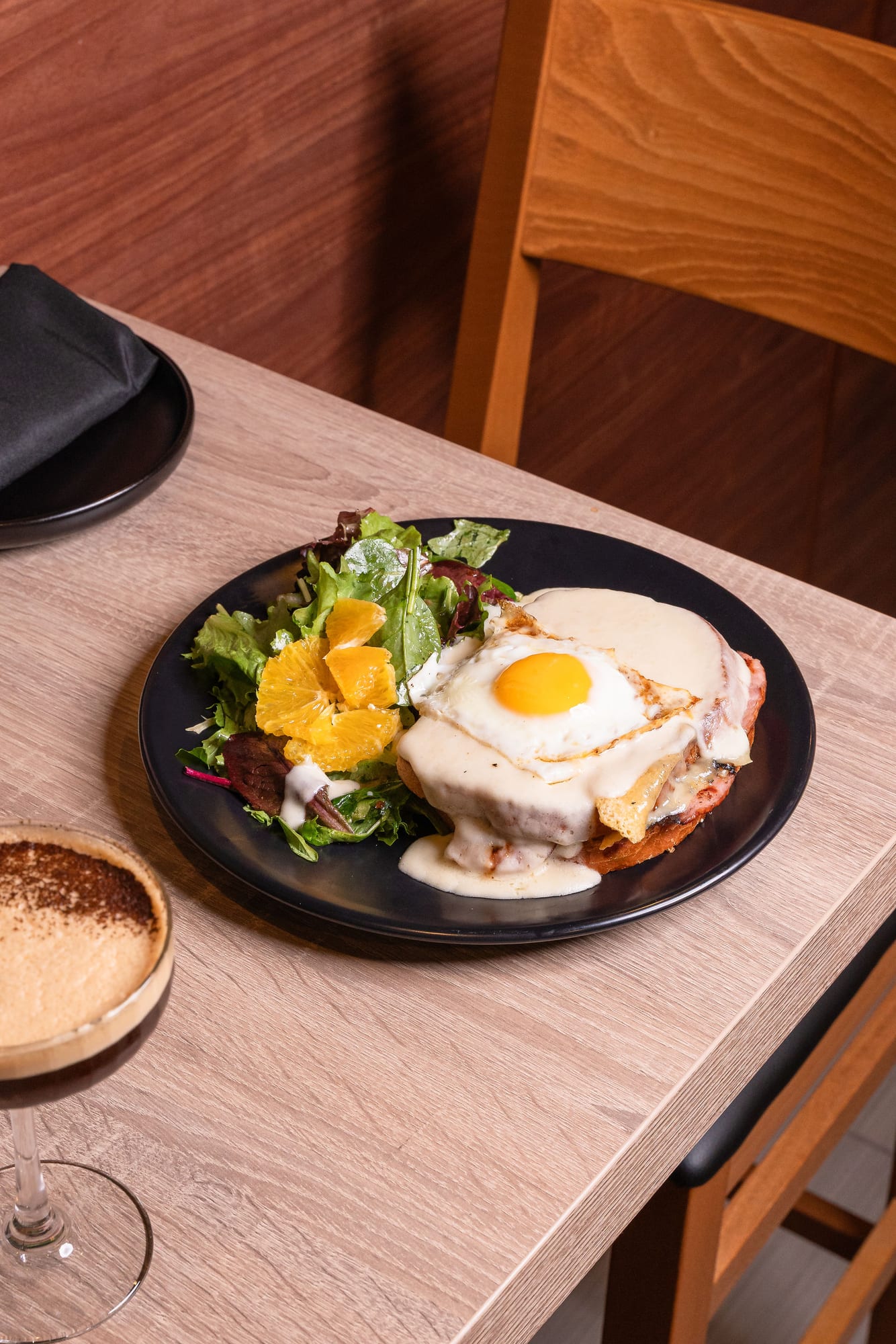 A poached egg and hollandaise over greens with an orange segment