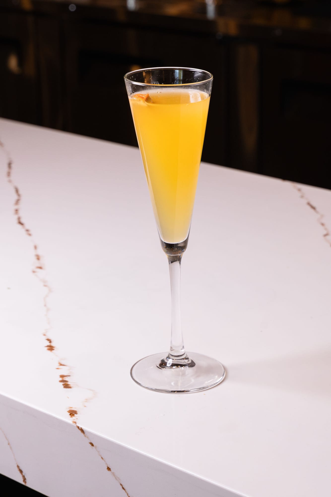 A mimosa in a champagne flute on the marble bar