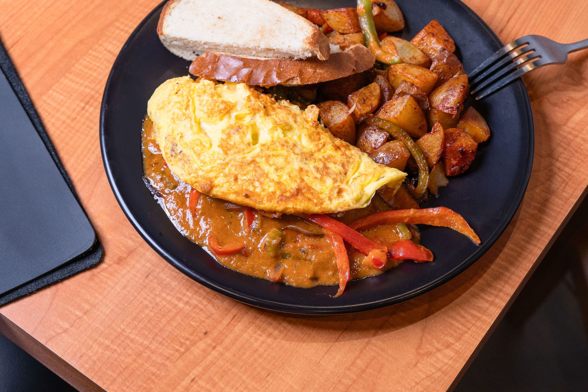 A folded omelette with crispy breakfast potatoes and toast
