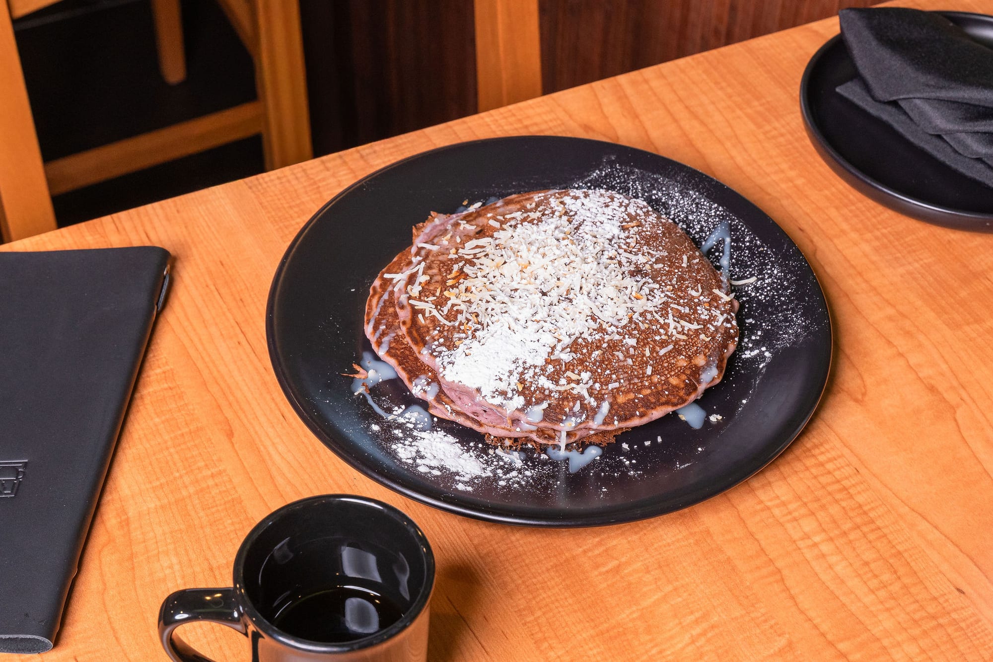 A stack of pancakes dusted with powdered sugar