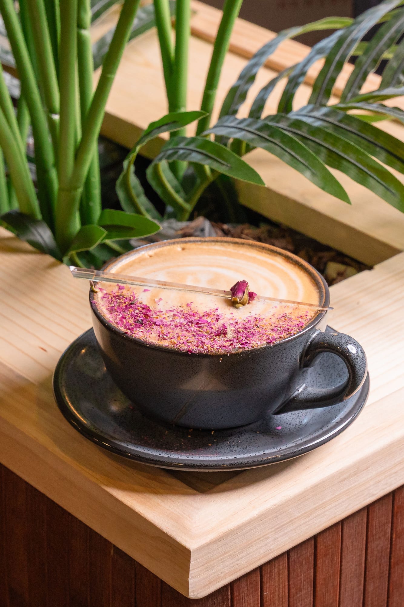 A rose latte in a wide cup, dusted with dried rose petals