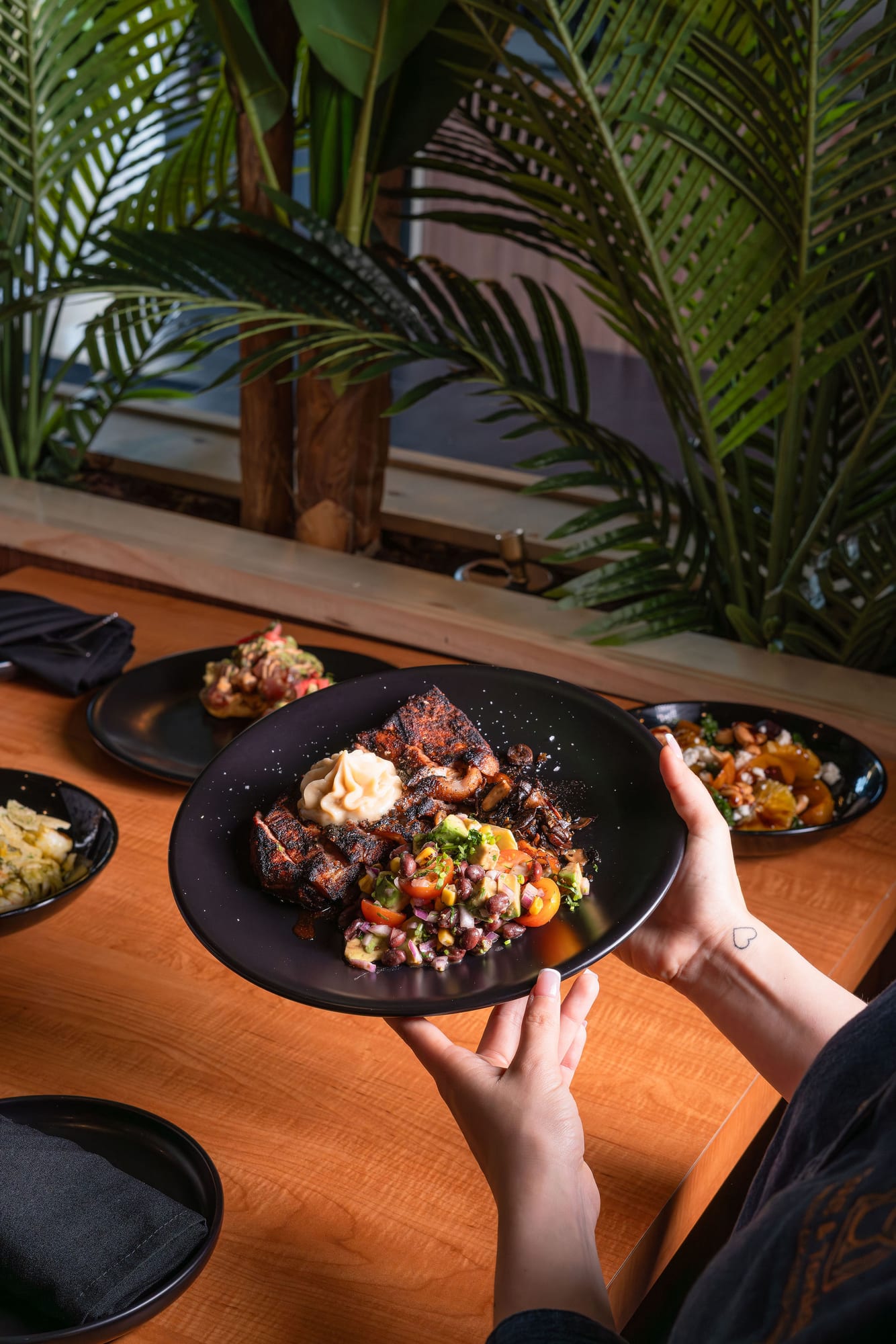 A braised short-rib plate held tableside above a spread of dishes