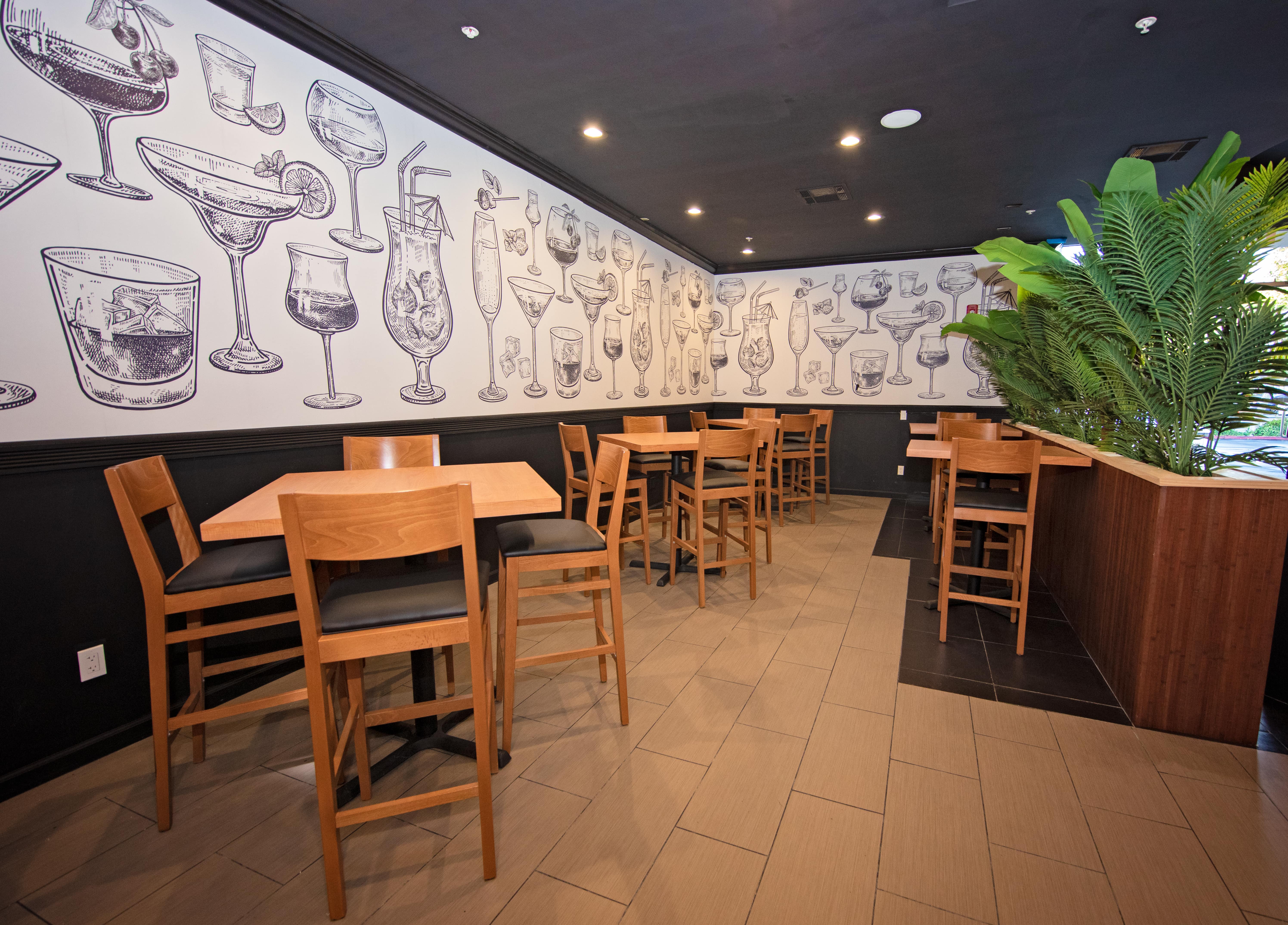 The private room with hand-drawn cocktail mural and high-top seating