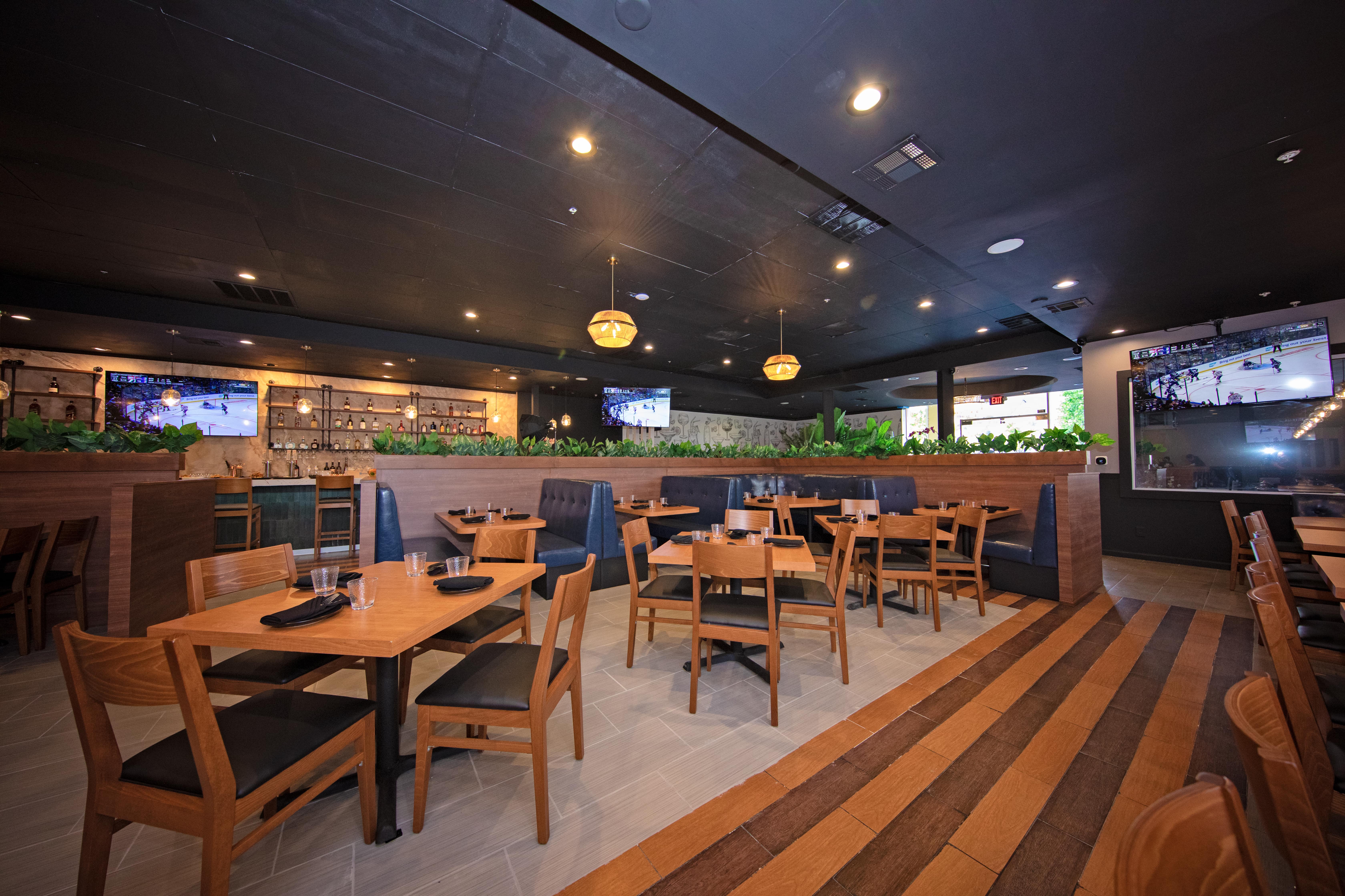 The main dining room with wood tables, pendant lights, and a striped wood floor