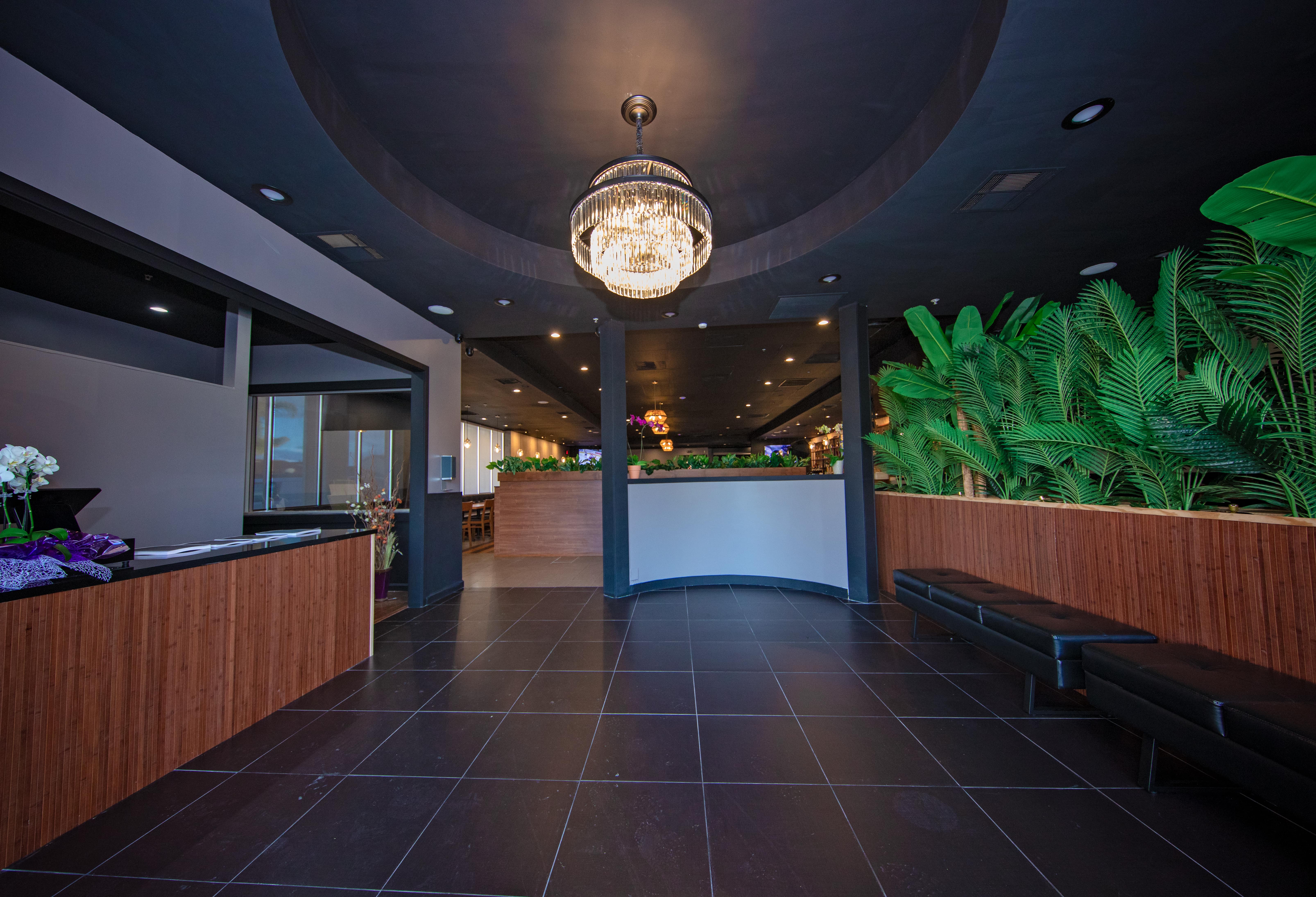 The lobby entrance with a crystal chandelier and a palm-lined wall