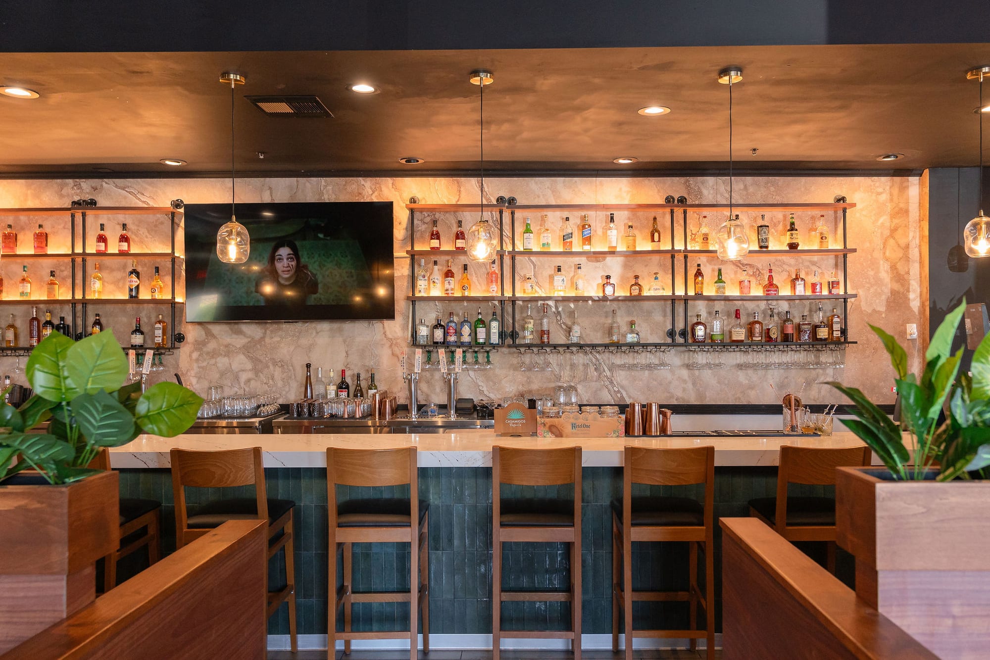 The backbar with full bottle shelving and a mounted screen