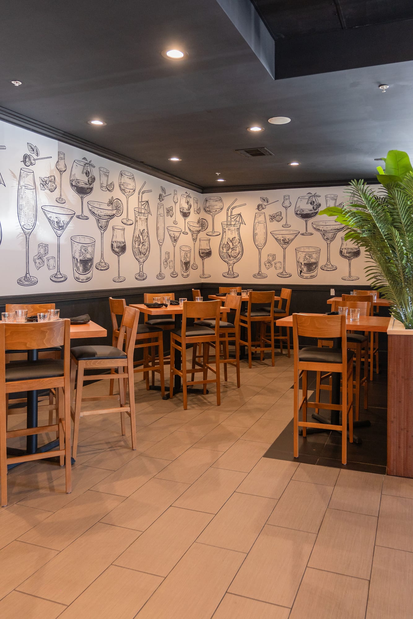 The private room lined with a hand-drawn cocktail mural and high-top seating